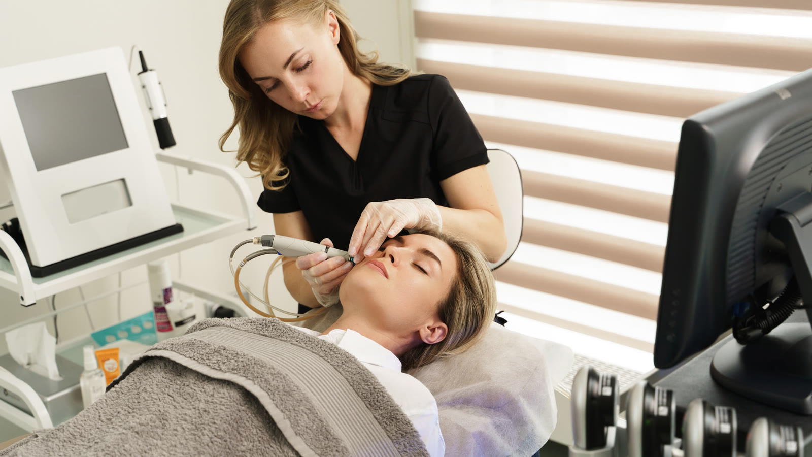 Cosmetologist doing a hydrafacial treatment with a beauty machine